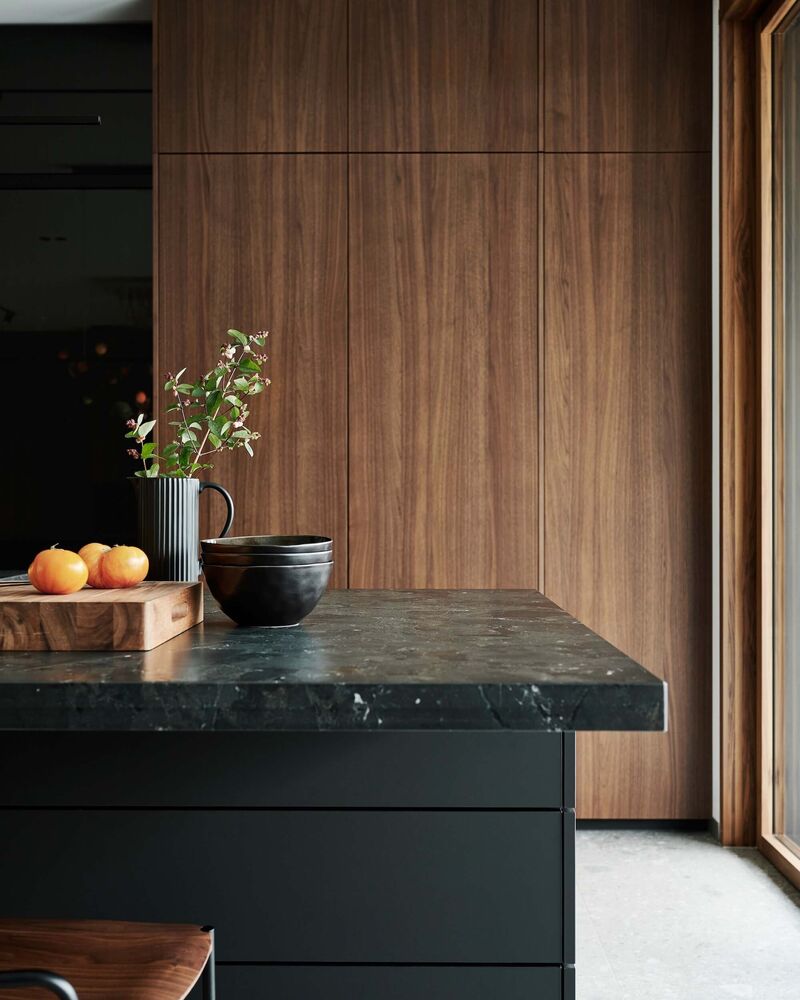 L'impression d'ensemble harmonieuse est obtenue grâce aux portes coulissantes et aux panneaux muraux, qui sont fabriqués à partir de l'élégant placage des façades de cuisine.